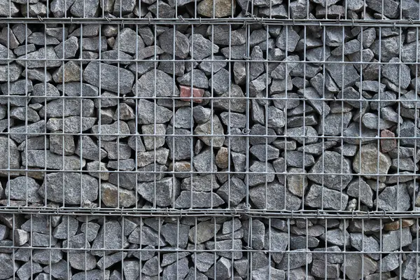 Galvanize ağ içinde harabe taşı. Geçmişi. Duvarları örmek için taşlardan örülmüş Gabion şiltesi. Ağlı taşlar, dekoratif duvarlar, güçlendirme