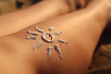 SPF, plajdaki güneş yanıklarından deriyi korur. Güneşin güneş kreminden yapılmış bir kadının bacağına çizilmesi. Kumsalda dinlenmek. Yazın plajda bronzlaşmak için krem. Rahatlama kavramı