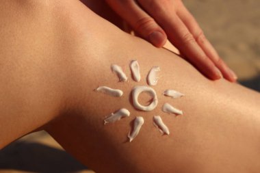 SPF, plajdaki güneş yanıklarından deriyi korur. Güneşin güneş kreminden yapılmış bir kadının bacağına çizilmesi. Kumsalda dinlenmek. Yazın plajda bronzlaşmak için krem. Rahatlama kavramı