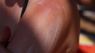 Cildine güneş kremi süren bir kadın. Yaz, sahil, bronzlaşma. Plajda mayo giyen bir kadın. Krem cildi güneş yanığından, bronzlaşmadan ve kremden korur. Plajda yaz tatili