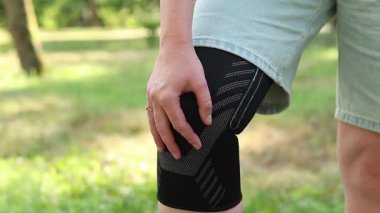 Spor dizliği takmış kadın bacaklarının yakın çekimi. Yaralandıktan sonra giymek için elastik dizlik, uzun yürüyüşler ya da spor yaparken eklem desteği gerekli. Sargı bezi. Kız dizindeki bandajı düzeltiyor.