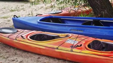 Kyiv, Ukrayna - 27 Temmuz 2025: Kayıklar suyun yakınındaki kumda uzanıyorlar. Yazın aktif bir eğlence. Turist rotası, hobi, su sporları için kano kiralama. Sahilde renkli kanolar