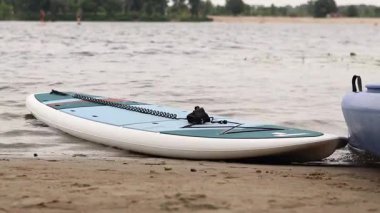 Kyiv, Ukrayna - 29 Temmuz 2025: Suda yüzmek için SUP tahtaları nehir kıyısında uzanır. Yazın aktif bir eğlence. Seyahat güzergahı, hobi ve su sporları için arazi aracı kiralama. Rüzgarlı hava