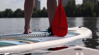 Kyiv, Ukrayna - 4 Ağustos 2025: Ayakta duran kadın bacaklarının yakın çekimi. Stand-up 'a binen bir kız. Aktif yaz tatili. Su sporları. Stand-up 'taki kız.