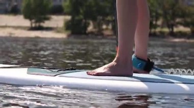 Kyiv, Ukrayna - 4 Ağustos 2025: Ayakta duran kadın bacaklarının yakın çekimi. Stand-up 'a binen bir kız. Aktif yaz tatili. Su sporları. Stand-up 'taki kız.
