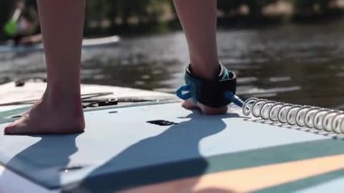 Kyiv, Ukrayna - 4 Ağustos 2025: Ayakta duran kadın bacaklarının yakın çekimi. Stand-up 'a binen bir kız. Aktif yaz tatili. Su sporları. Stand-up 'taki kız.
