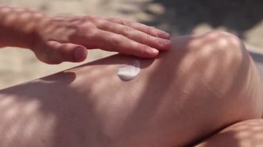 Cilde güneş kremi sürerken yaklaş. SPF koruması. Dişi el güneş ışınlarının saldırgan etkilerinden korunmak için cilde SPF kremi sürer. Plaj tatili Güvenli bronzlaşma