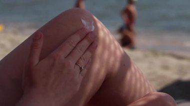 Cilde güneş kremi sürerken yaklaş. SPF koruması. Dişi el güneş ışınlarının saldırgan etkilerinden korunmak için cilde SPF kremi sürer. Plaj tatili Güvenli bronzlaşma