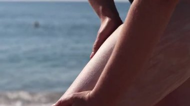 Cilde güneş kremi sürerken yaklaş. SPF koruması. Dişi el güneş ışınlarının saldırgan etkilerinden korunmak için cilde SPF kremi sürer. Plaj tatili Güvenli bronzlaşma