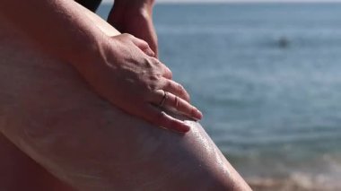 Cilde güneş kremi sürerken yaklaş. SPF koruması. Dişi el güneş ışınlarının saldırgan etkilerinden korunmak için cilde SPF kremi sürer. Plaj tatili Güvenli bronzlaşma
