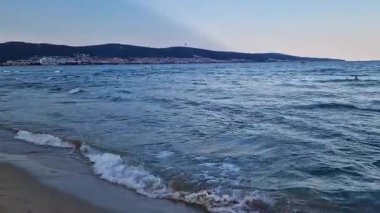 Kıyıya yakın denizde dalgalar. Deniz akşam manzarası. Bulgaristan ve Pomorie kenti yakınlarındaki Karadeniz. Kıyıya yakın bir yerde köpüklü dalgalar salla. Tatil köyünde tatil kavramı. Plaj tatili