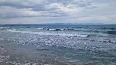 Denizde fırtınalı bir hava, yakından gelen dalgalar. Bulgaristan ve Pomorie kenti yakınlarındaki Karadeniz. Akşamları kıyıya yakın denizde dalgalar. Deniz akşam manzarası. Tatil köyünde tatil kavramı