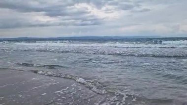 Denizde fırtınalı bir hava, yakından gelen dalgalar. Bulgaristan ve Pomorie kenti yakınlarındaki Karadeniz. Akşamları kıyıya yakın denizde dalgalar. Deniz akşam manzarası. Tatil köyünde tatil kavramı