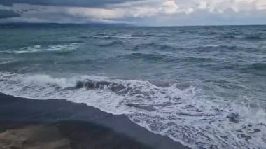 Denizde fırtınalı bir hava, yakından gelen dalgalar. Bulgaristan ve Pomorie kenti yakınlarındaki Karadeniz. Akşamları kıyıya yakın denizde dalgalar. Deniz akşam manzarası. Tatil köyünde tatil kavramı