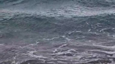 Denizde fırtınalı bir hava, yakından gelen dalgalar. Bulgaristan ve Pomorie kenti yakınlarındaki Karadeniz. Akşamları kıyıya yakın denizde dalgalar. Deniz akşam manzarası. Tatil köyünde tatil kavramı