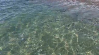 Kıyıya yakın denizde dalgalar. Deniz Burnu. Kıyıya yakın bir yerde köpüklü dalgalar salla. Plajdaki temiz su manzarası. Tatil köyünde tatil kavramı. Yaz tatilinde. Suyun üzerinde güneş parlıyor.