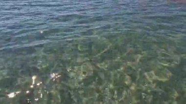 Kıyıya yakın denizde dalgalar. Deniz Burnu. Kıyıya yakın bir yerde köpüklü dalgalar salla. Plajdaki temiz su manzarası. Tatil köyünde tatil kavramı. Yaz tatilinde. Suyun üzerinde güneş parlıyor.