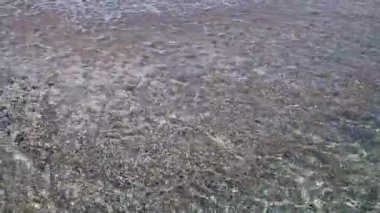 Kıyıya yakın denizde dalgalar. Deniz Burnu. Kıyıya yakın bir yerde köpüklü dalgalar salla. Plajdaki temiz su manzarası. Tatil köyünde tatil kavramı. Yaz tatilinde. Suyun üzerinde güneş parlıyor.