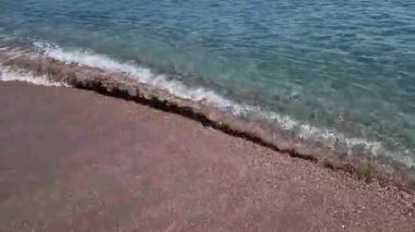 Kıyıya yakın denizde dalgalar. Deniz Burnu. Kıyıya yakın bir yerde köpüklü dalgalar salla. Plajdaki temiz su manzarası. Tatil köyünde tatil kavramı. Yaz tatilinde. Suyun üzerinde güneş parlıyor.