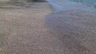 Kıyıya yakın denizde dalgalar. Deniz Burnu. Kıyıya yakın bir yerde köpüklü dalgalar salla. Plajdaki temiz su manzarası. Tatil köyünde tatil kavramı. Yaz tatilinde. Suyun üzerinde güneş parlıyor.