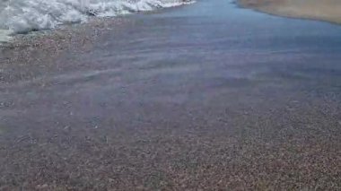 Kıyıya yakın denizde dalgalar. Deniz Burnu. Kıyıya yakın bir yerde köpüklü dalgalar salla. Plajdaki temiz su manzarası. Tatil köyünde tatil kavramı. Yaz tatilinde. Suyun üzerinde güneş parlıyor.