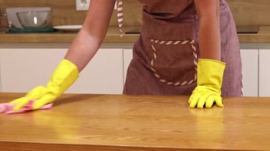 Önlüklü ve sarı eldivenli bir kadın, tozu ve toprağı yapışkan bir peçeteyle siliyor. Daireyi temizliyorum. Temizlik servisi. Ellerinizi temizleme eldivenleriyle yakın plan çekin. Temizleyici