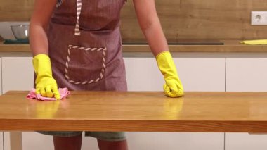 Önlüklü ve sarı eldivenli bir kadın, tozu ve toprağı yapışkan bir peçeteyle siliyor. Daireyi temizliyorum. Temizlik servisi. Ellerinizi temizleme eldivenleriyle yakın plan çekin. Temizleyici