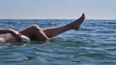 Şişme şeffaf bir dairede denizde yüzen kız. Plajda şişirilebilir bir çemberin dışına çıkmış dişi bacaklar. Denizde yaz tatili. Hafta sonu tatil köyünde. İnce kadın bacakları.
