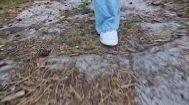 Beyaz spor ayakkabılarla ormanın zemininden yürüyen kadın bacakları. Yaz yürüyüşü. Doğa yürüyüşü. Parkta yürüyen bacaklar. Ön manzara. Akşam yürüyüşü temiz havada