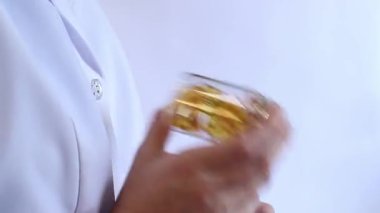 Cam kavanozu balık yağı kapsülleriyle tutan bir doktorun yakın çekimi. Omega-3. Eczacı, terapist ya da elinde ilaç olan beyaz önlüklü bir doktor. Balık yağı hapları. Tıbbi ve sağlık hizmeti kavramı
