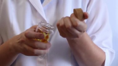 Cam kavanozu balık yağı kapsülleriyle tutan bir doktorun yakın çekimi. Omega-3. Eczacı, terapist ya da elinde ilaç olan beyaz önlüklü bir doktor. Balık yağı hapları. Tıbbi ve sağlık hizmeti kavramı