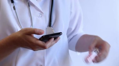 Cam kavanozda ve akıllı telefonda vitamin tutan bir doktorun yakın çekimi. Eczacı cep telefonuna bilgi yazıyor. Bir hemşirenin ellerine ilaçlarla yakın çekim.