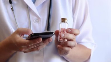 Cam kavanozda ve akıllı telefonda vitamin tutan bir doktorun yakın çekimi. Eczacı cep telefonuna bilgi yazıyor. Bir hemşirenin ellerine ilaçlarla yakın çekim.