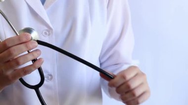Stetoskop tutan bir doktorun yakın çekimi. Bir hemşirenin ellerine steteskopla yakın çekim, beyaz önlüklü bir doktor veya terapist. Sağlık ve tıp konsepti. Tıbbi aletli bir terapist.