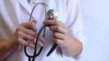 Stetoskop tutan bir doktorun yakın çekimi. Bir hemşirenin ellerine steteskopla yakın çekim, beyaz önlüklü bir doktor veya terapist. Sağlık ve tıp konsepti. Tıbbi aletli bir terapist.