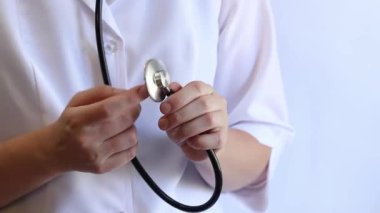 Stetoskop tutan bir doktorun yakın çekimi. Bir hemşirenin ellerine steteskopla yakın çekim, beyaz önlüklü bir doktor veya terapist. Sağlık ve tıp konsepti. Tıbbi aletli bir terapist.