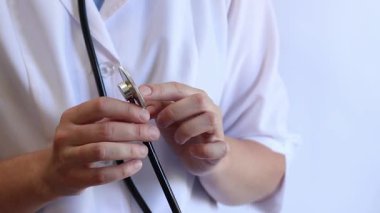 Stetoskop tutan bir doktorun yakın çekimi. Bir hemşirenin ellerine steteskopla yakın çekim, beyaz önlüklü bir doktor veya terapist. Sağlık ve tıp konsepti. Tıbbi aletli bir terapist.