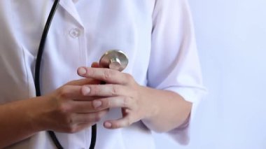 Stetoskop tutan bir doktorun yakın çekimi. Bir hemşirenin ellerine steteskopla yakın çekim, beyaz önlüklü bir doktor veya terapist. Sağlık ve tıp konsepti. Tıbbi aletli bir terapist.