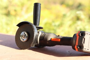 Akülü bileme makinesi. Elektrikli alet, yakın plan. Açı öğütücü verandada. Tamir ve inşaat aletleri. Saplı açı öğütücü