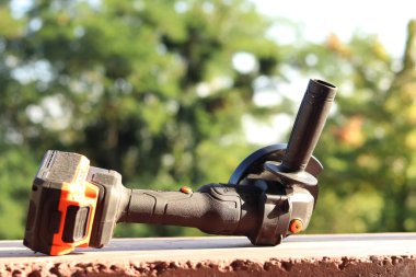 Akülü bileme makinesi. Elektrikli alet, yakın plan. Açı öğütücü verandada. Tamir ve inşaat aletleri. Saplı açı öğütücü