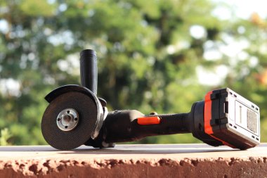 Akülü bileme makinesi. Elektrikli alet, yakın plan. Açı öğütücü verandada. Tamir ve inşaat aletleri. Saplı açı öğütücü