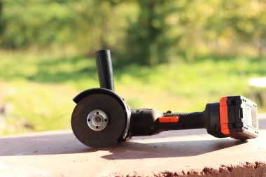 Akülü bileme makinesi. Elektrikli alet, yakın plan. Açı öğütücü verandada. Tamir ve inşaat aletleri. Saplı açı öğütücü