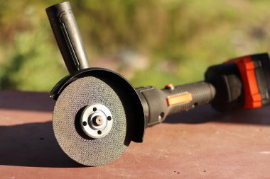 Akülü bileme makinesi. Elektrikli alet, yakın plan. Açı öğütücü verandada. Tamir ve inşaat aletleri. Saplı açı öğütücü