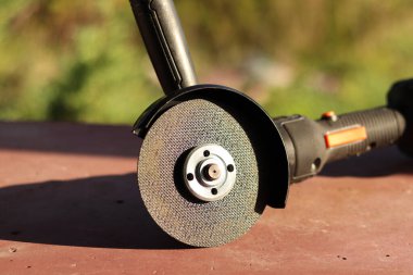 Akülü bileme makinesi. Elektrikli alet, yakın plan. Açı öğütücü verandada. Tamir ve inşaat aletleri. Saplı açı öğütücü