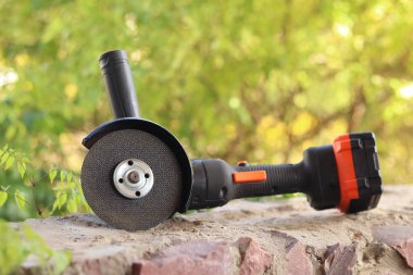 Akülü bileme makinesi. Elektrikli alet, yakın plan. Açı öğütücü verandada. Tamir ve inşaat aletleri. Saplı açı öğütücü