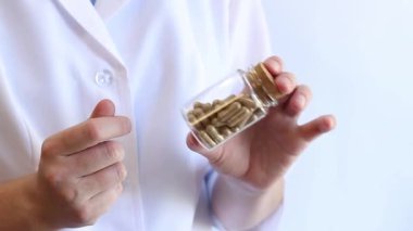 Doktor elinde ilaç kapsüllü cam bir kavanoz tutuyor. Elinde haplar olan beyaz önlüklü bir terapist ya da eczacı. İlaçlar. Küçük cam kavanozlarda beslenme takviyeleri. Hemşire ilaçları kontrol ediyor.