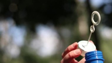 Tanınmayan kız sabun köpüğü üflüyor. Sabun köpükleri yakın plan. Parkta sabun köpüğü üflemek. Sokakta sabun köpüğü üfleyen bir kadın. Yaz tatili konsepti, huzurlu atmosfer