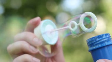 Tanınmayan kız sabun köpüğü üflüyor. Sabun köpükleri yakın plan. Parkta sabun köpüğü üflemek. Sokakta sabun köpüğü üfleyen bir kadın. Yaz tatili konsepti, huzurlu atmosfer