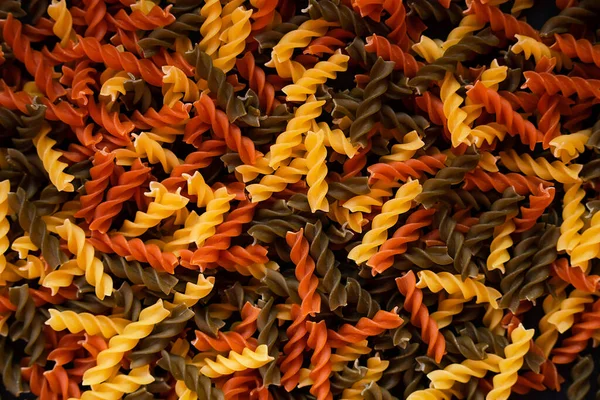 Üç renkli fusilli macunu spiral şekli. Makarna arkaplanı. Üst Manzara. Kapatın. Seçici odak.