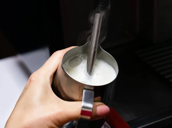 stock image Barista girl froths milk on a coffee machine for making cappuccino or latte. The concept of making drinks from natural coffee. Close-up. Selective focus.